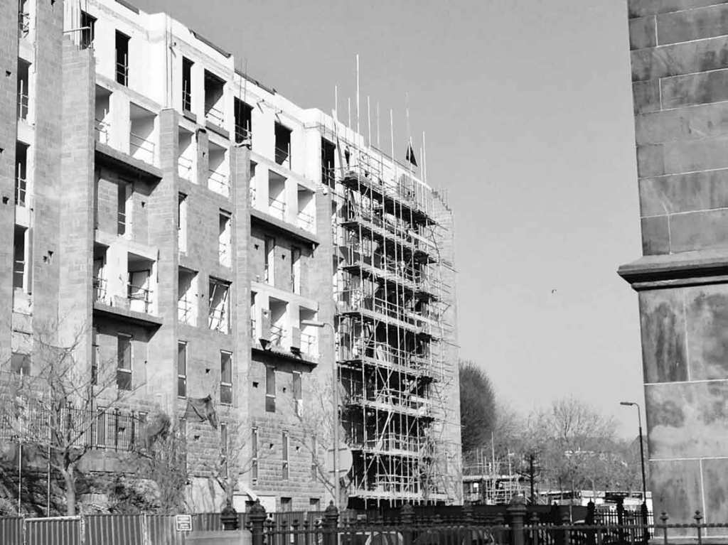 Building development with black flag flying on high scaffold, looking quite tiny, in black and white